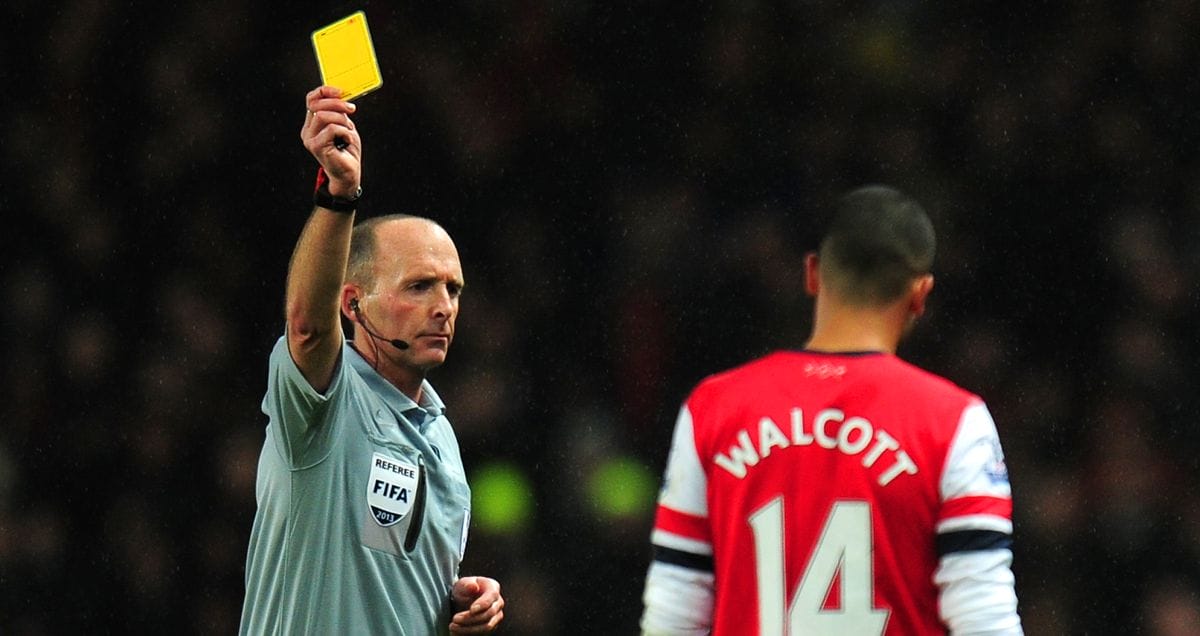 Mike Dean books Arsenal forward Theo Walcott during their game against Chelsea in December 2013